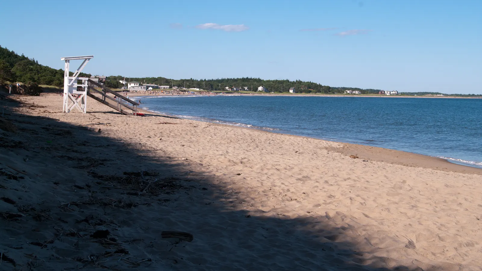 The wide sand sweep of Popham Beach State Park, Maine, meeting calm ocean water below a forested point
